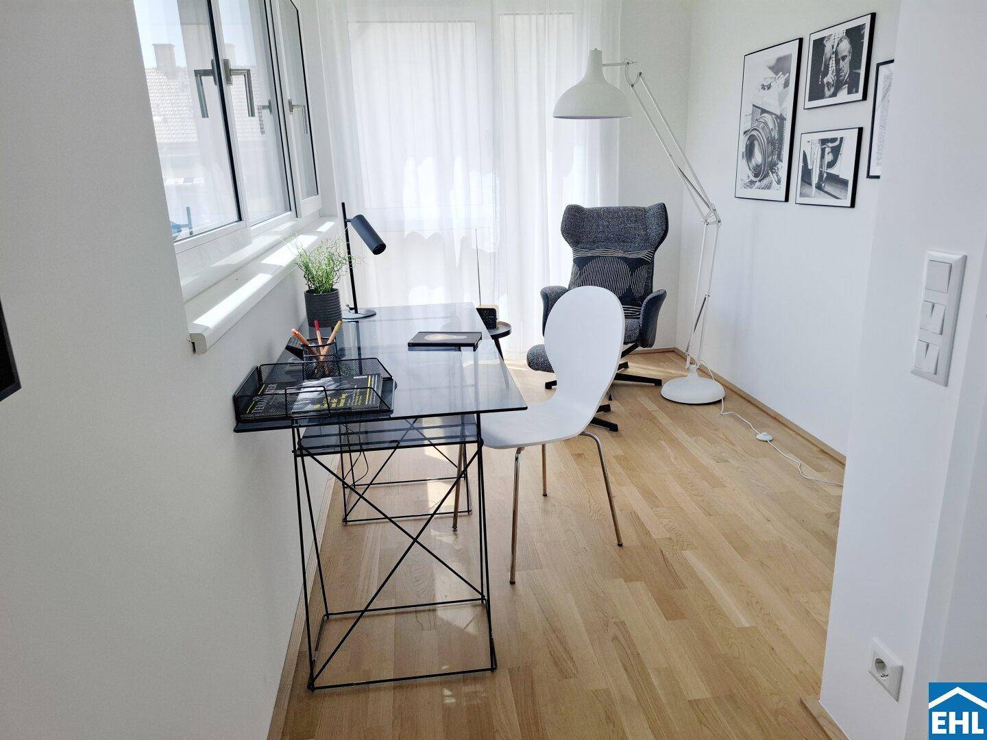Modernes Arbeitszimmer mit Holzboden, großem Fenster und minimalistischer Einrichtung.