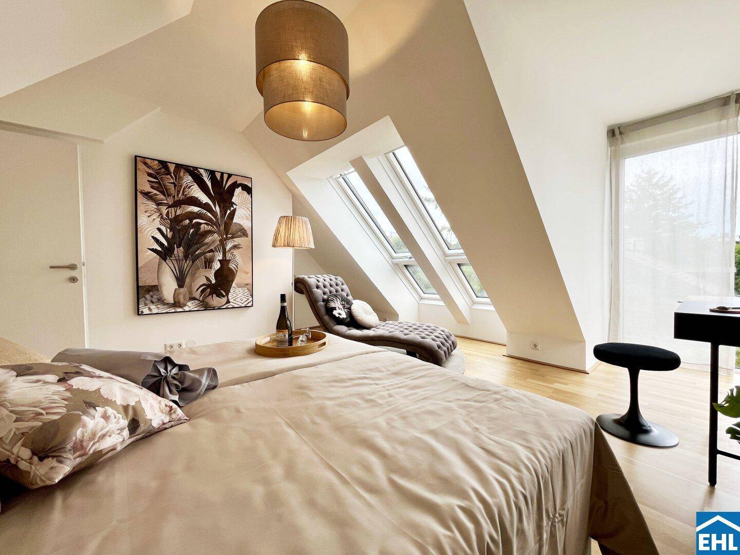 Helles Schlafzimmer mit Dachschrägen, Holzboden und großen Dachfenstern für viel Tageslicht.