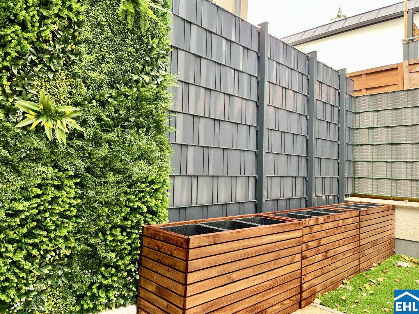Terrasse mit vertikaler Begrünung, Pflanzkübeln und modernem Sichtschutz.