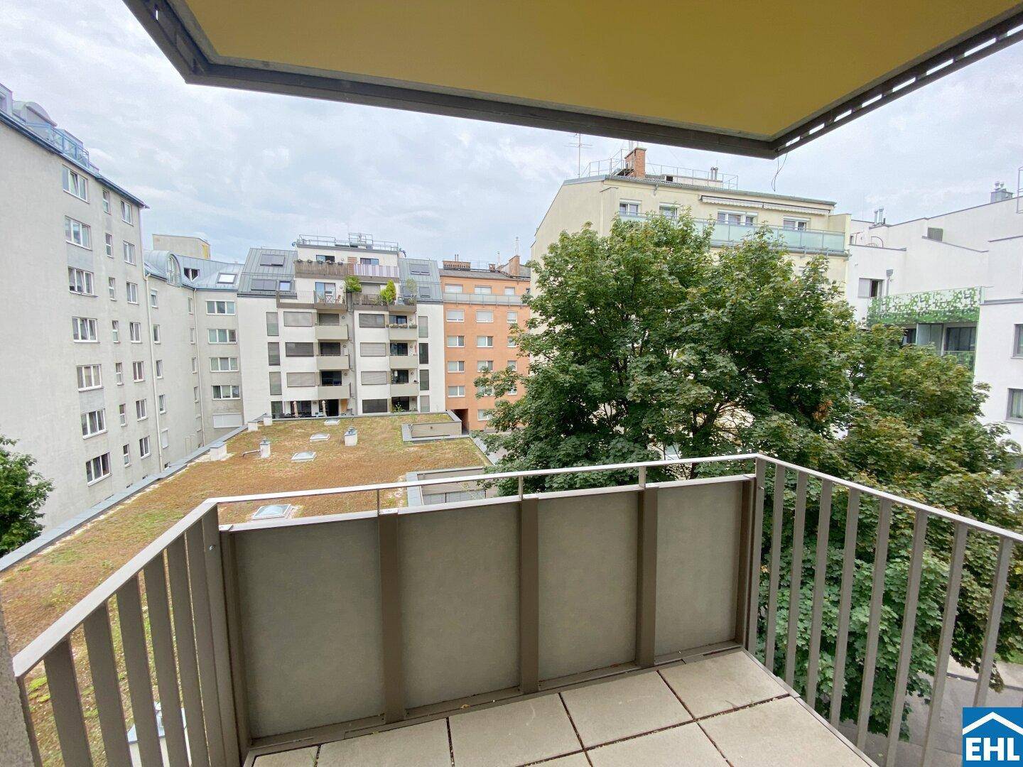 Balkon mit Blick auf umliegende Gebäude und grüne Bäume in der Stadt.