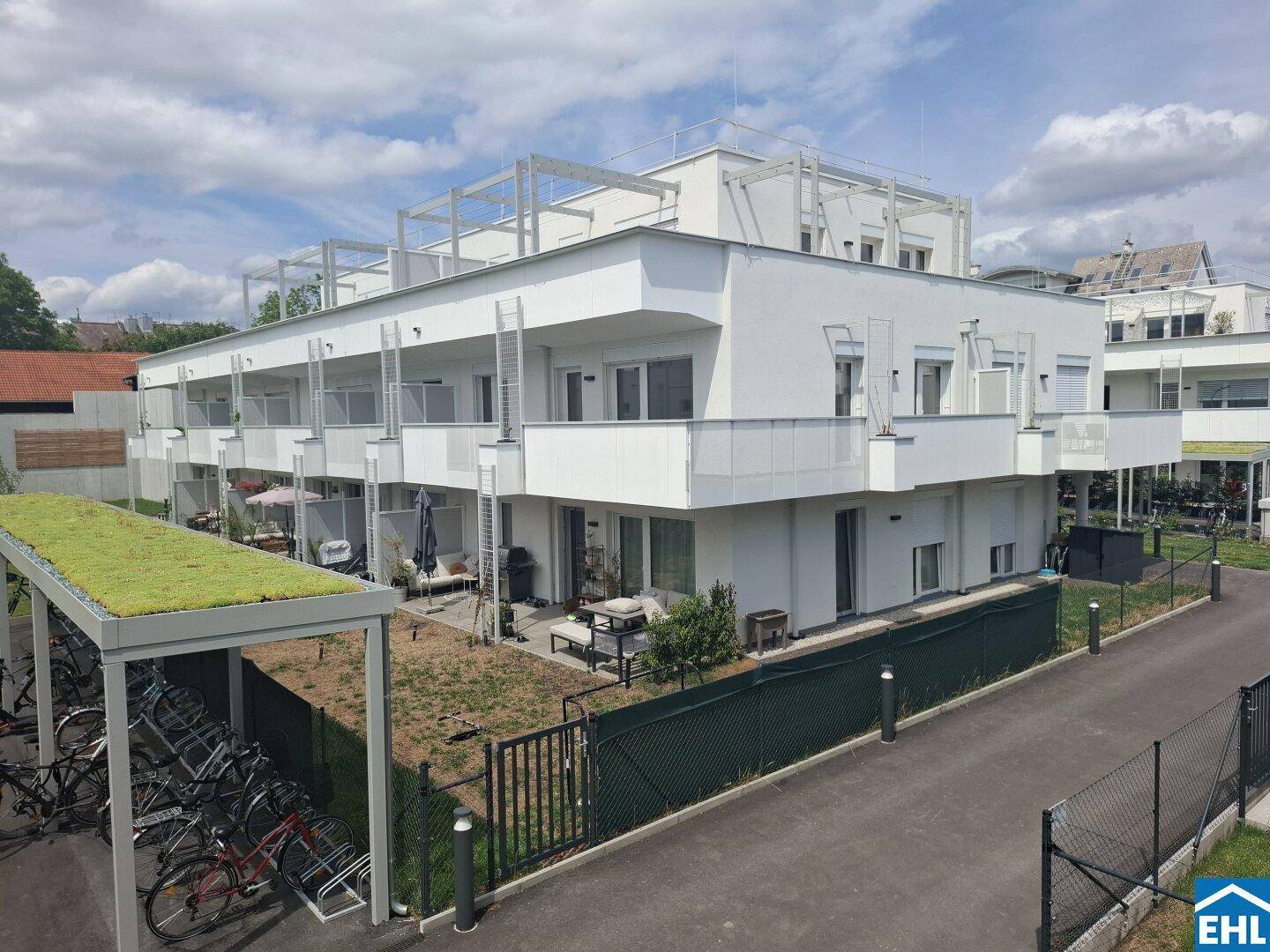 Moderne Wohnanlage mit weißen Fassaden, Balkonen, Terrassen und Fahrradabstellplätzen.