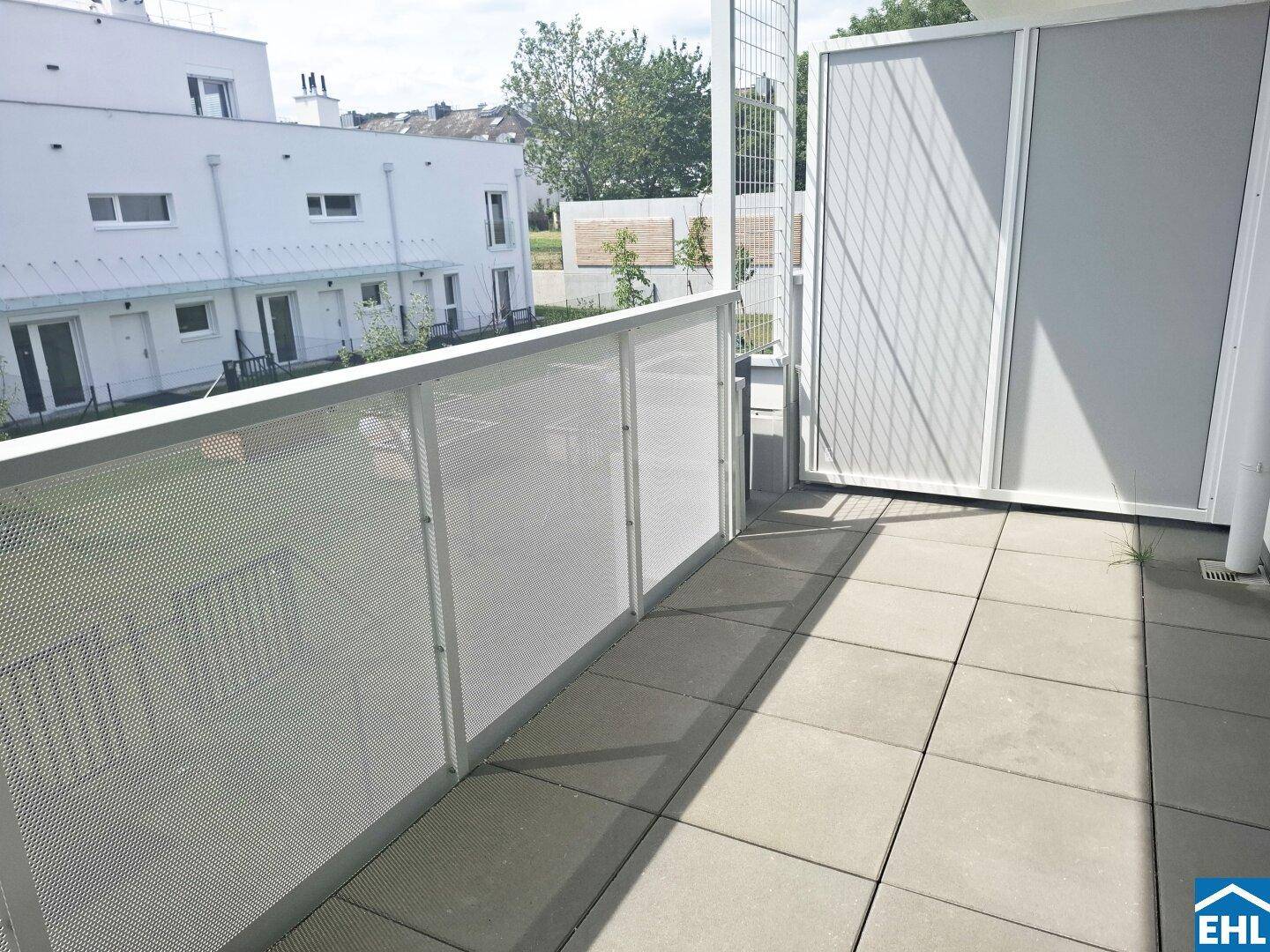 Heller Balkon mit Fliesenboden und moderner Metallbrüstung, bietet Blick auf die Umgebung.