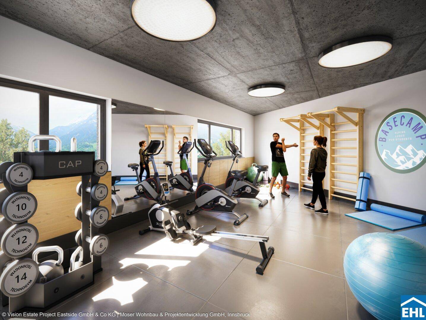 Moderner Fitnessraum mit verschiedenen Trainingsgeräten und Blick auf die umliegende Berglandschaft.