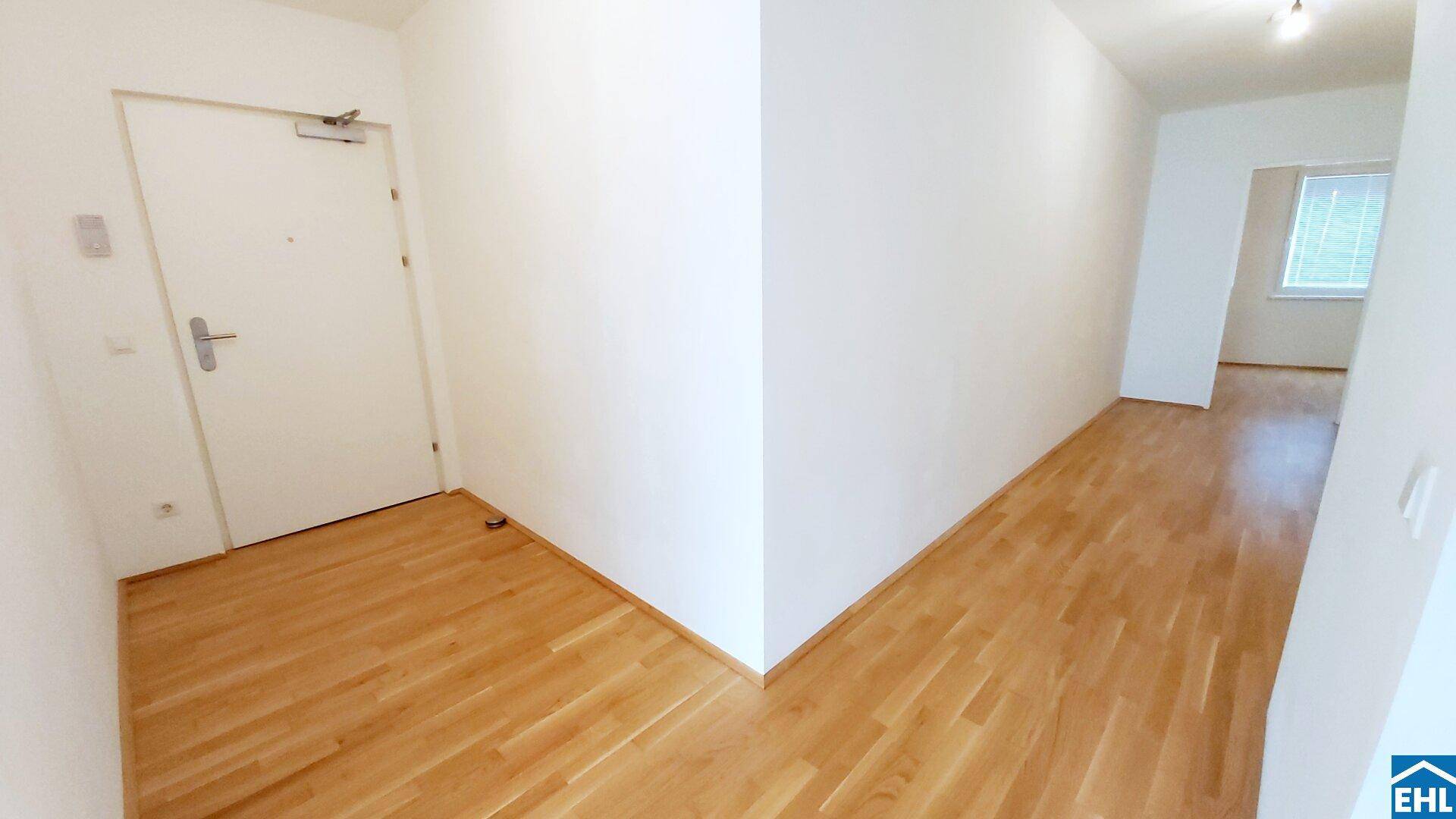 Heller Eingangsbereich und Flur mit Parkettboden und weiß gestrichenen Wänden.