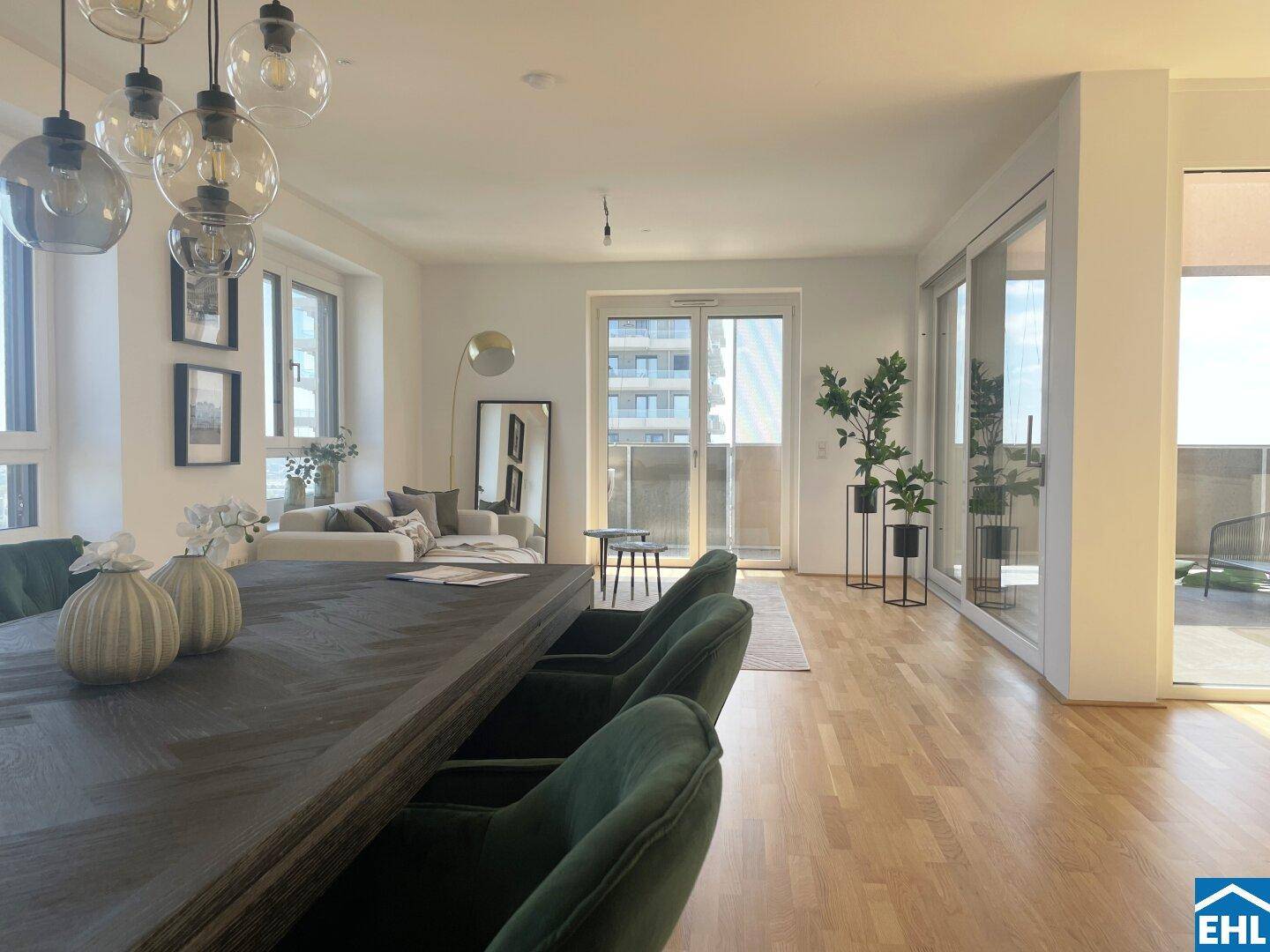 Offener Wohn-Essbereich mit Holzboden, elegantem Esstisch und Zugang zum Balkon.