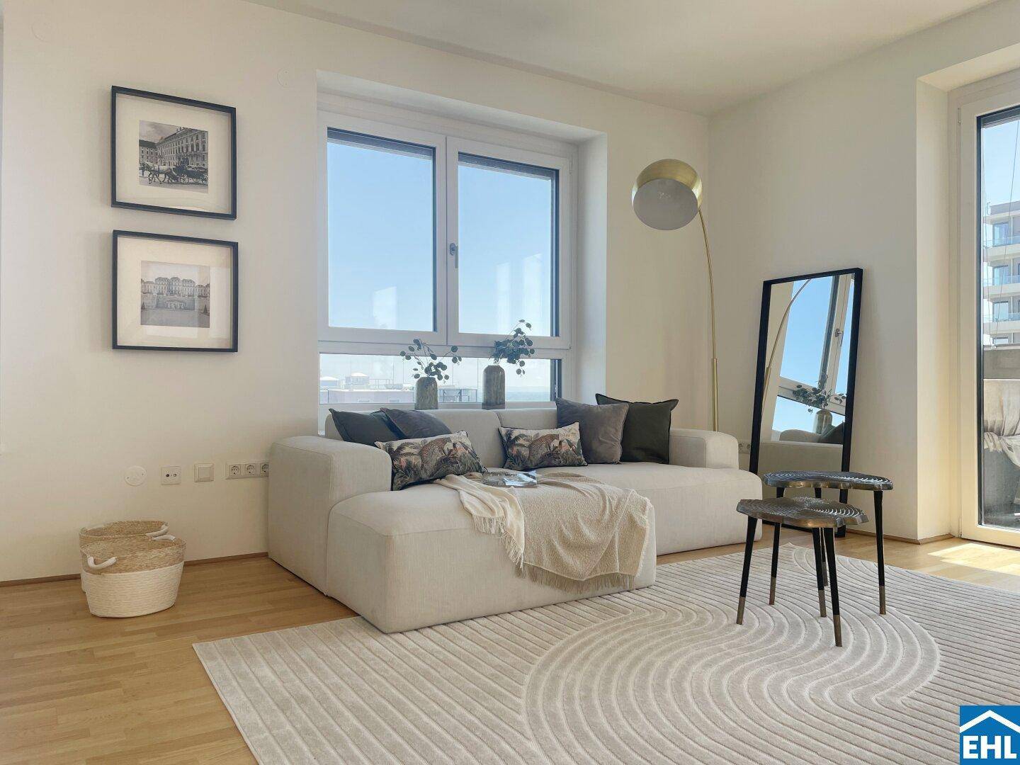 Helles Wohnzimmer mit beigem Sofa, Teppich und großen Fenstern für viel Tageslicht.