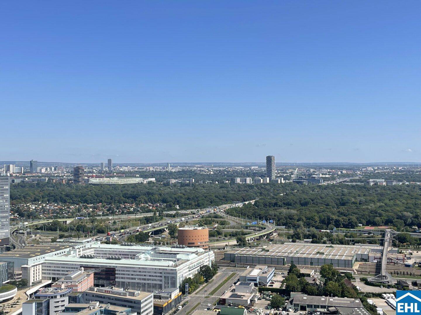 Panoramablick über die Stadt mit weiten Grünflächen und urbaner Infrastruktur.