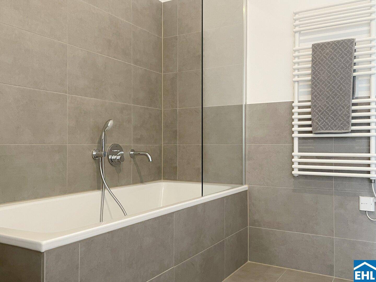 Modernes Badezimmer mit Badewanne, Duscharmatur und beheiztem Handtuchhalter.