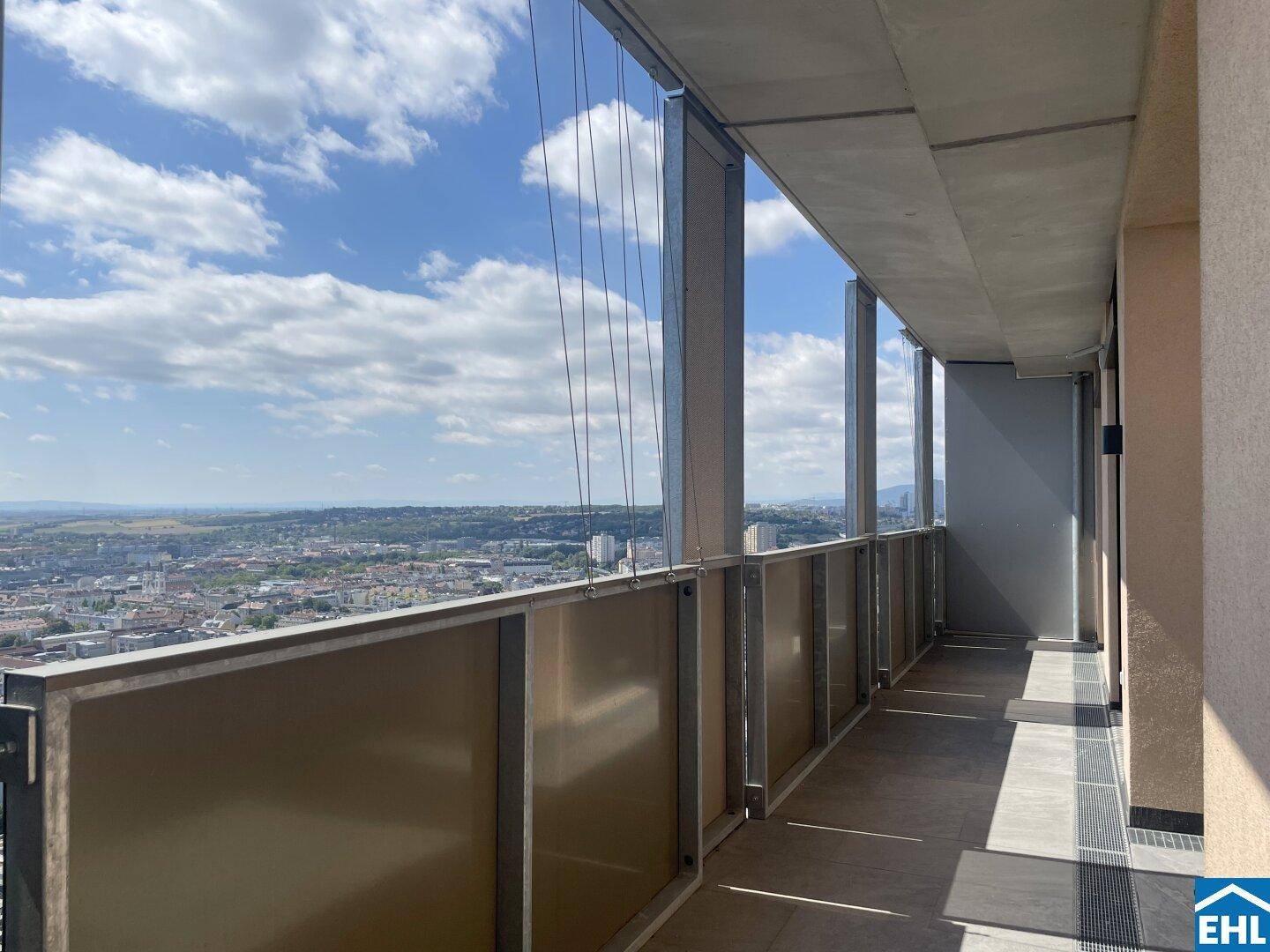 Langer Balkon mit Glasbrüstung und weitem Blick über die Stadtlandschaft.