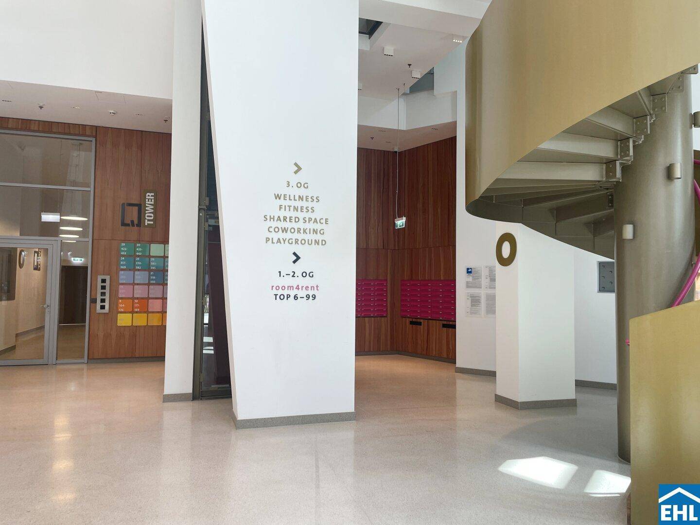 Moderne Lobby mit elegantem Design, Wendeltreppe und Hinweisschildern zu Gemeinschaftseinrichtungen.