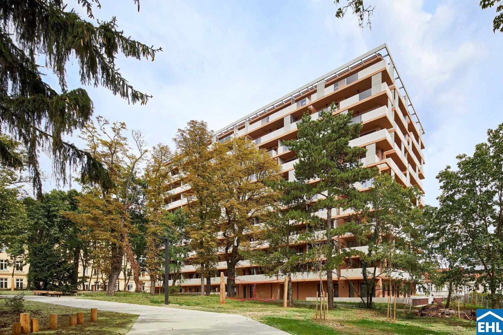 Großes, modernes Wohngebäude mit vielen Balkonen, umgeben von Bäumen und Grünflächen.