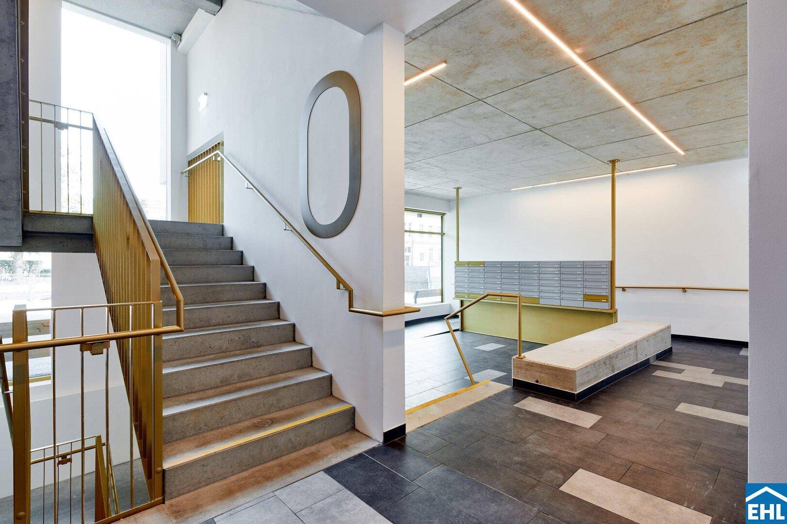 Moderner Eingangsbereich mit Treppe, Briefkästen und indirekter Beleuchtung in einem Neubau.