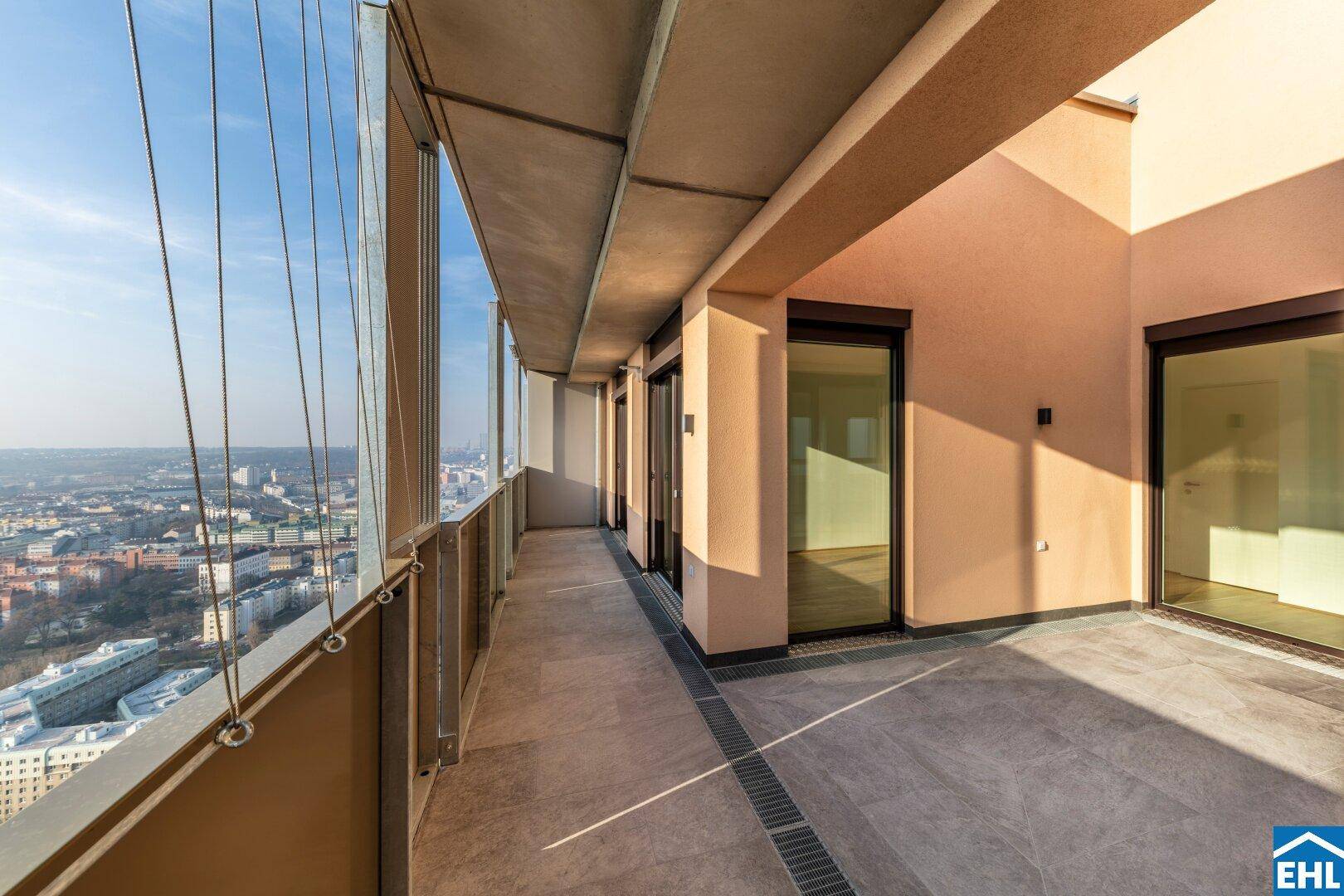 Lange Terrasse mit Fliesenboden und beeindruckendem Stadtblick von einem Hochhaus.