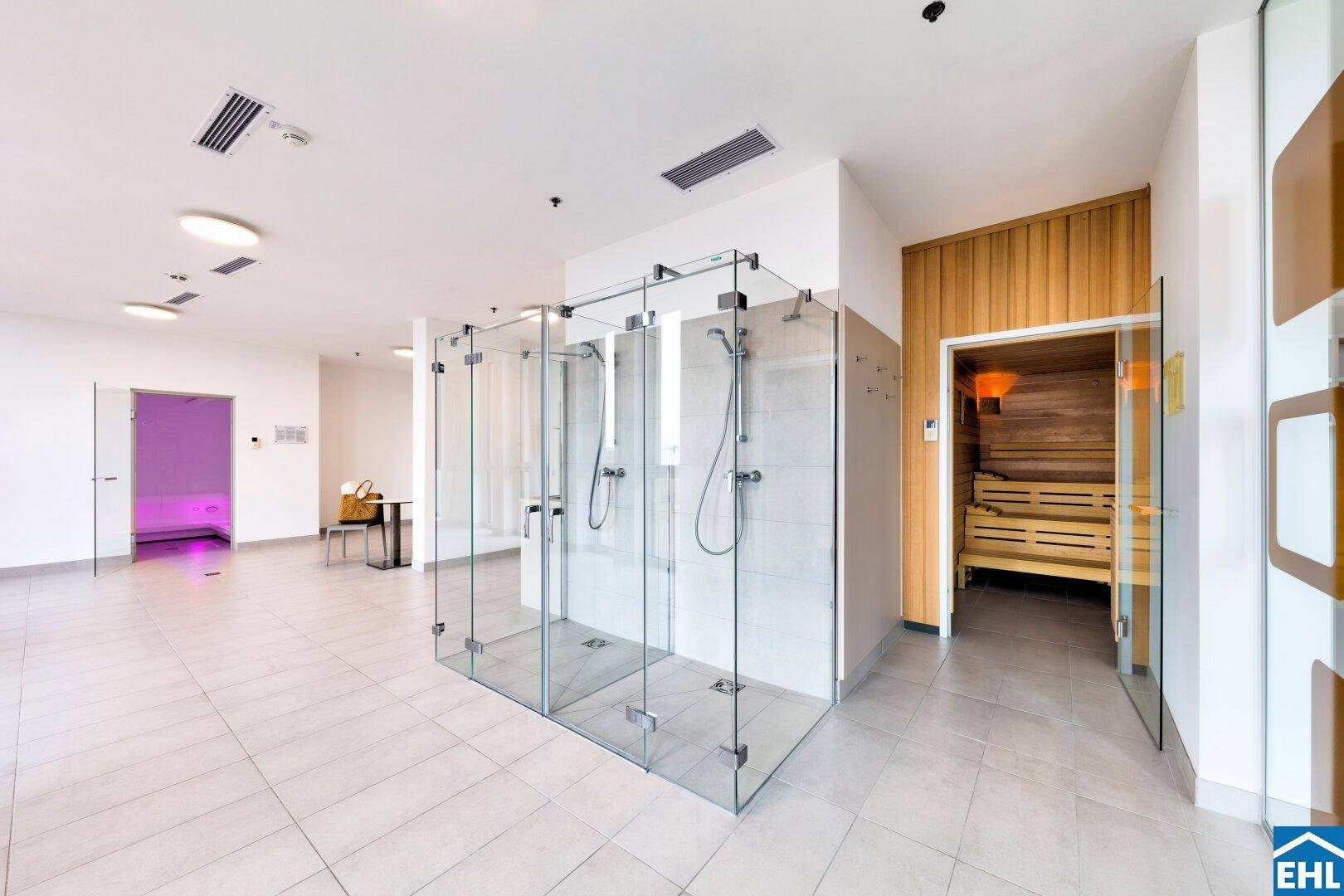 Moderner Wellnessbereich mit Glasduschen und einer holzvertäfelten Sauna für Entspannung.