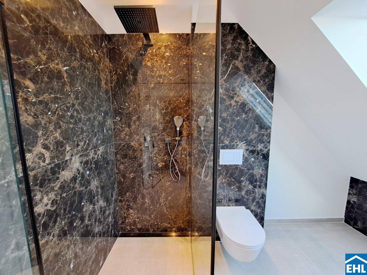 Elegante begehbare Dusche mit dunklen Marmorfliesen und wandhängendem WC in modernem Bad.