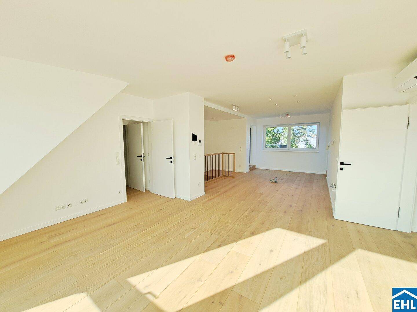 Helles, offenes Wohnzimmer mit Holzboden und viel Tageslicht, bereit für die Einrichtung.