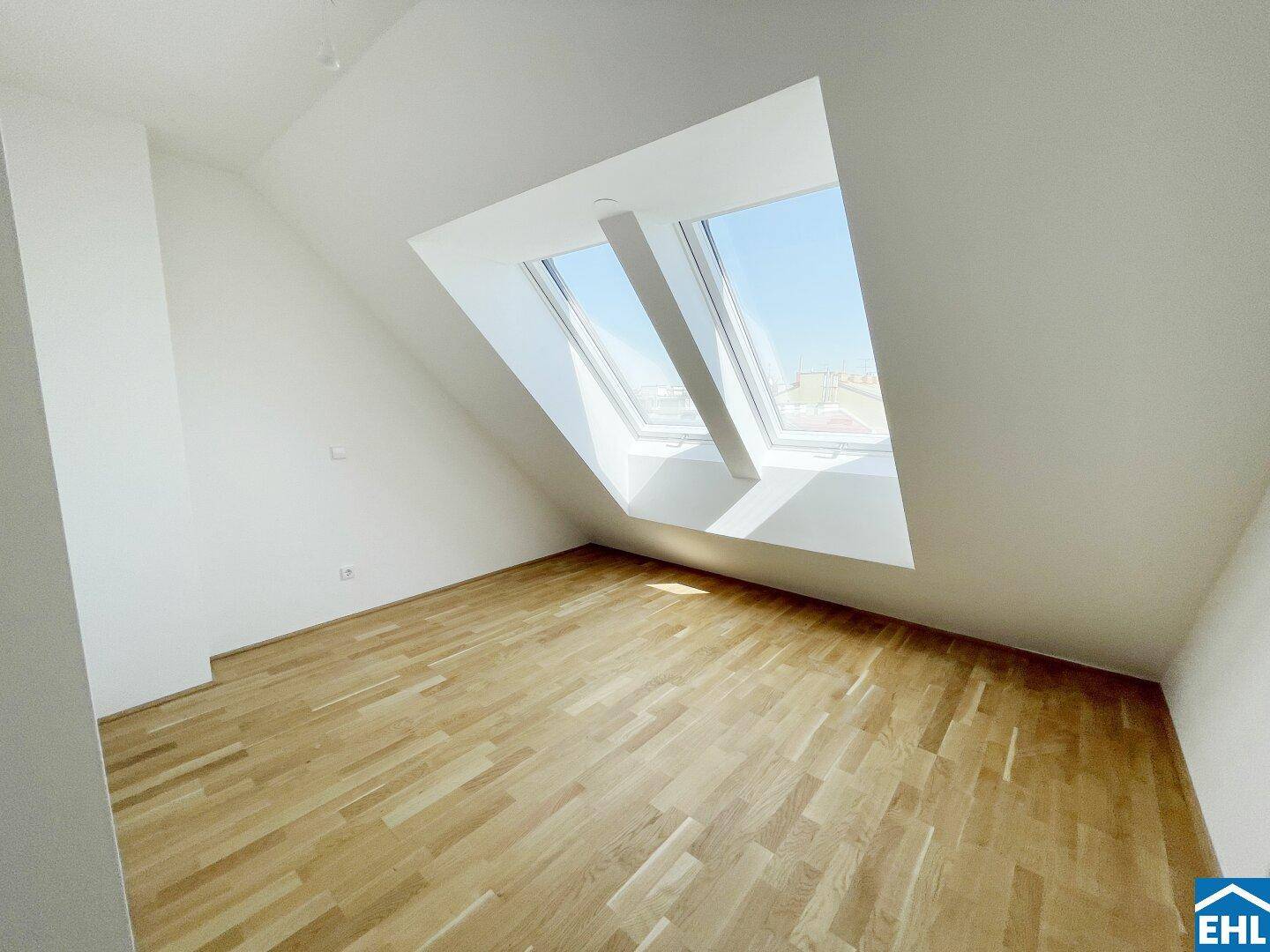Heller Raum im Dachgeschoss mit großen Dachfenstern und Holzboden, der eine weite Aussicht bietet.