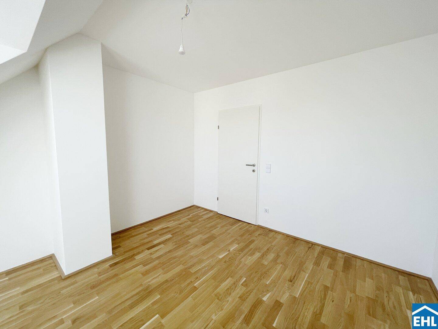 Schlichtes Schlafzimmer mit Holzboden und weiß gestrichenen Wänden, bereit zur individuellen Gestaltung.