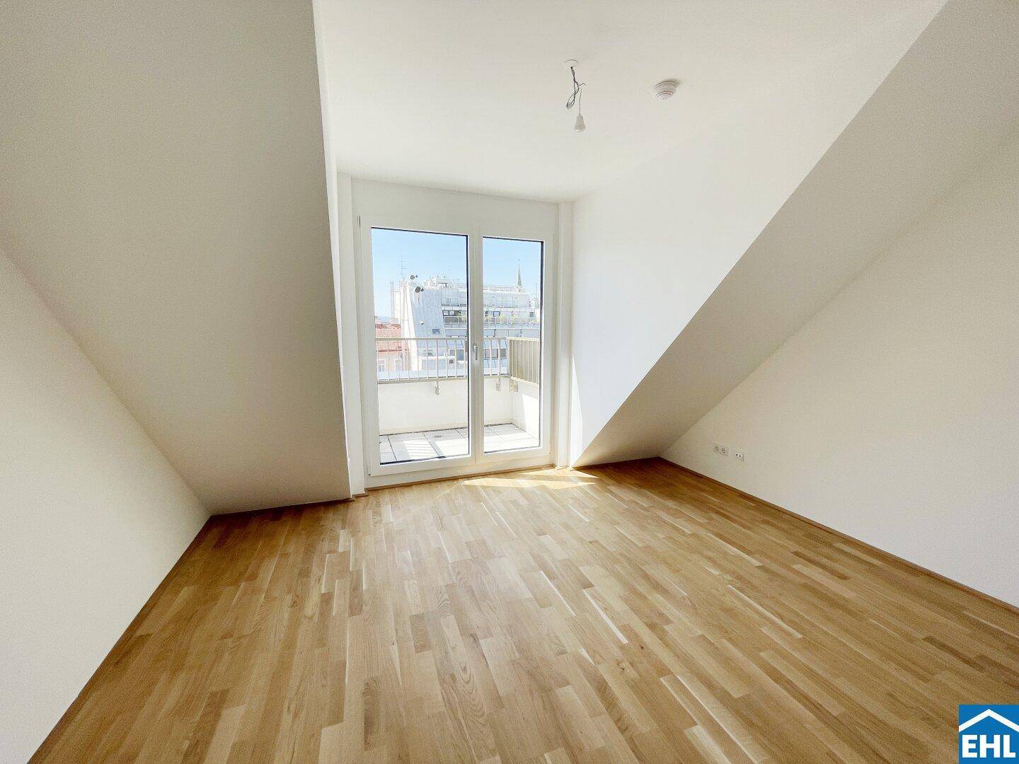 Helles Schlafzimmer mit Holzboden, Dachschrägen und direktem Zugang zu einem Balkon.