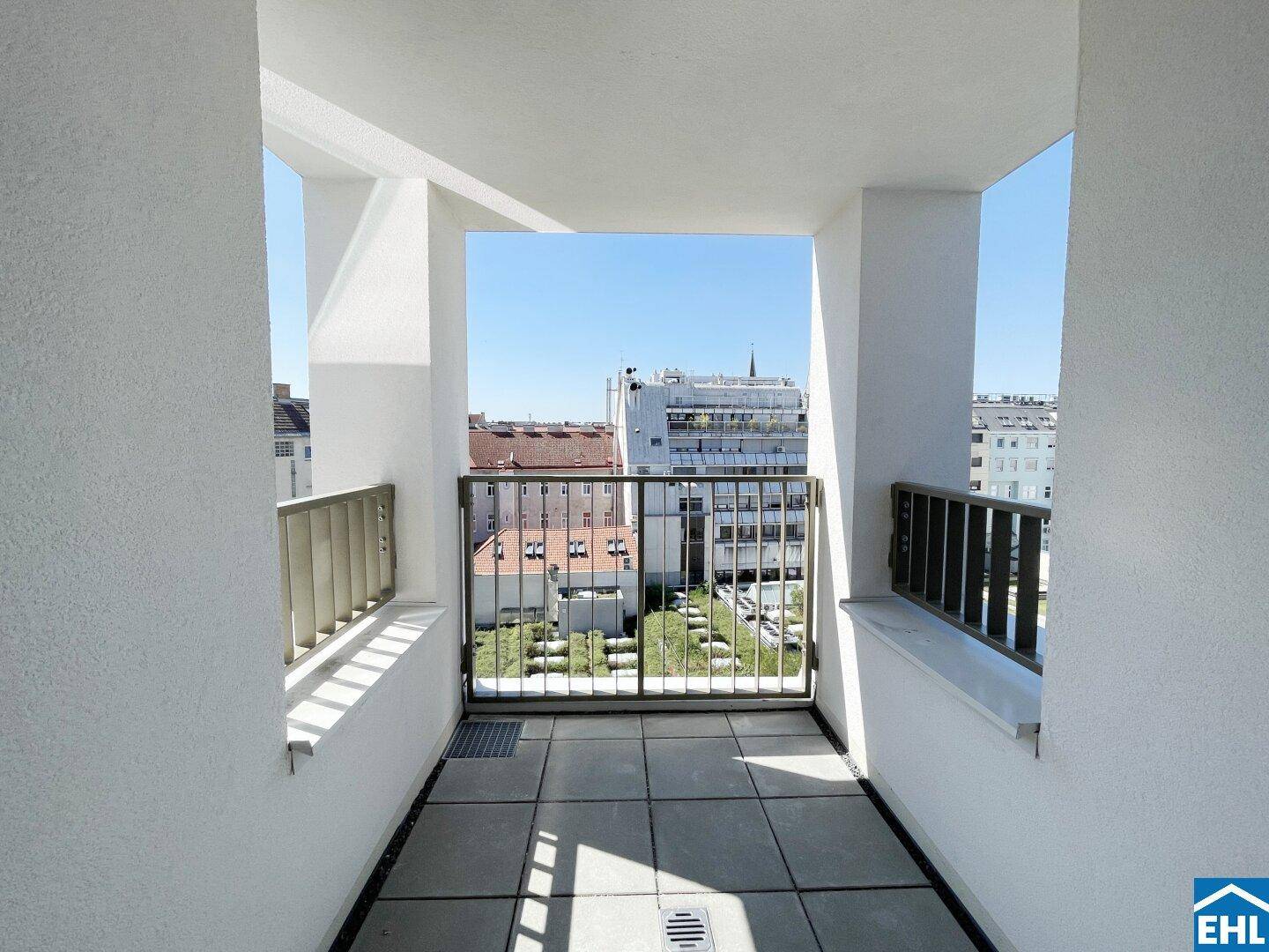 Überdachter Balkon mit Fliesenboden und Blick auf die umliegenden Gebäude und den Innenhof.