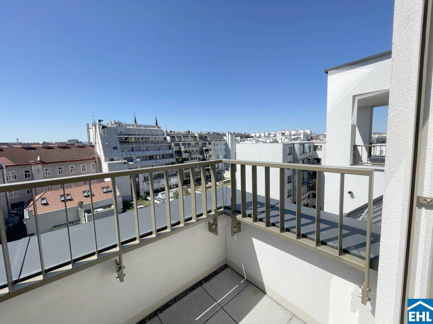 Geräumiger Balkon mit Metallgeländer und weitem Blick über die Dächer der Stadt.