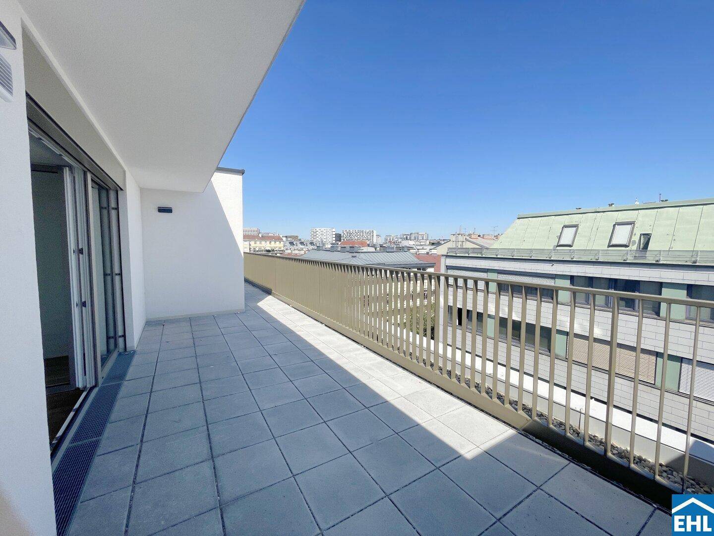Langer Balkon mit Fliesenboden und Metallgeländer, bietet einen weiten Blick über die Stadt.