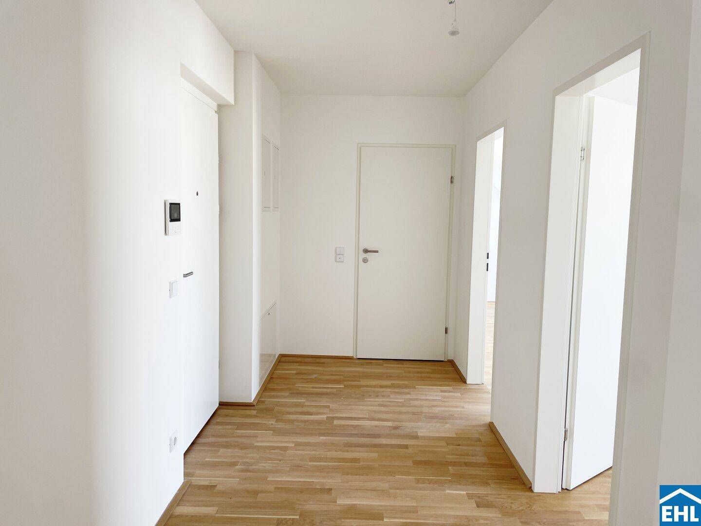 Heller Flur mit Holzboden und mehreren Türen, ausgestattet mit einer Gegensprechanlage.