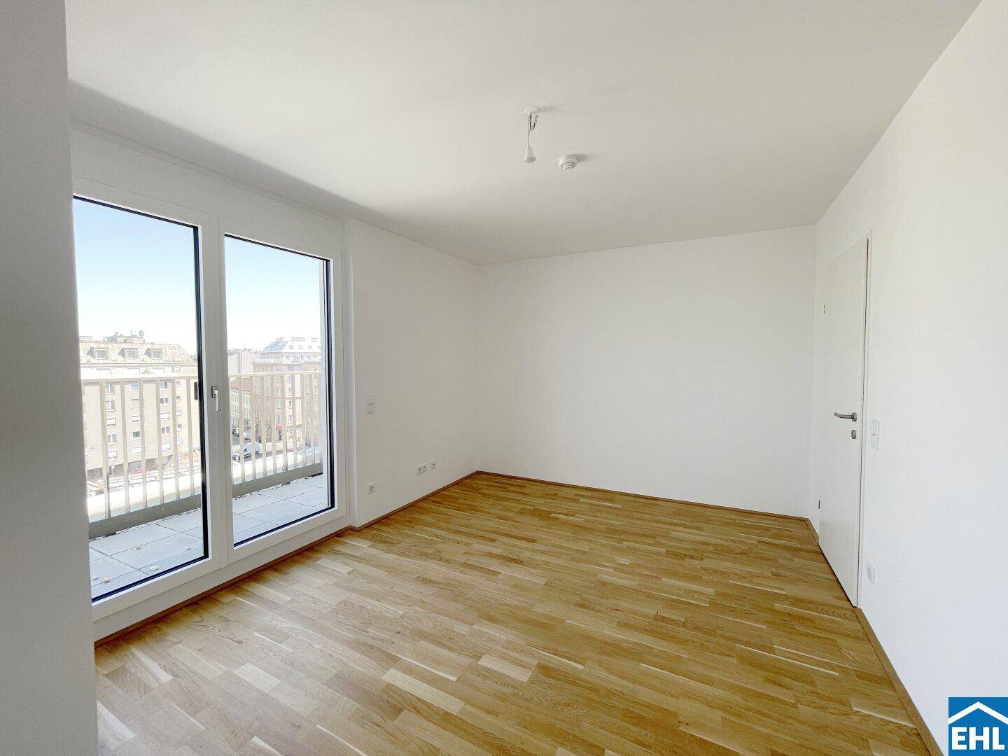 Helles Schlafzimmer mit Parkettboden, weiß gestrichenen Wänden und Zugang zu einem Balkon.