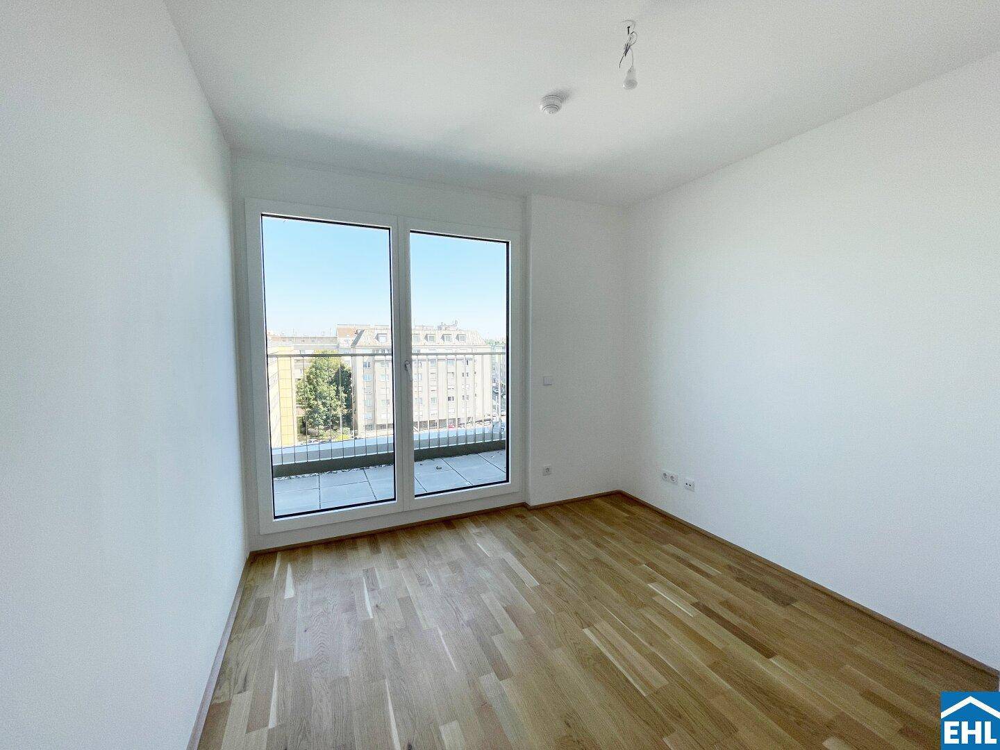 Geräumiges Schlafzimmer mit Parkettboden und großen Fenstern, die einen weiten Stadtblick bieten.