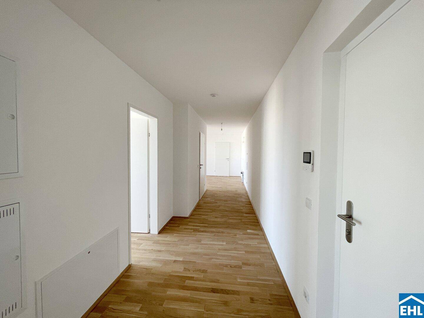 Langer, heller Flur mit Parkettboden und mehreren Türen, der die Räume verbindet.