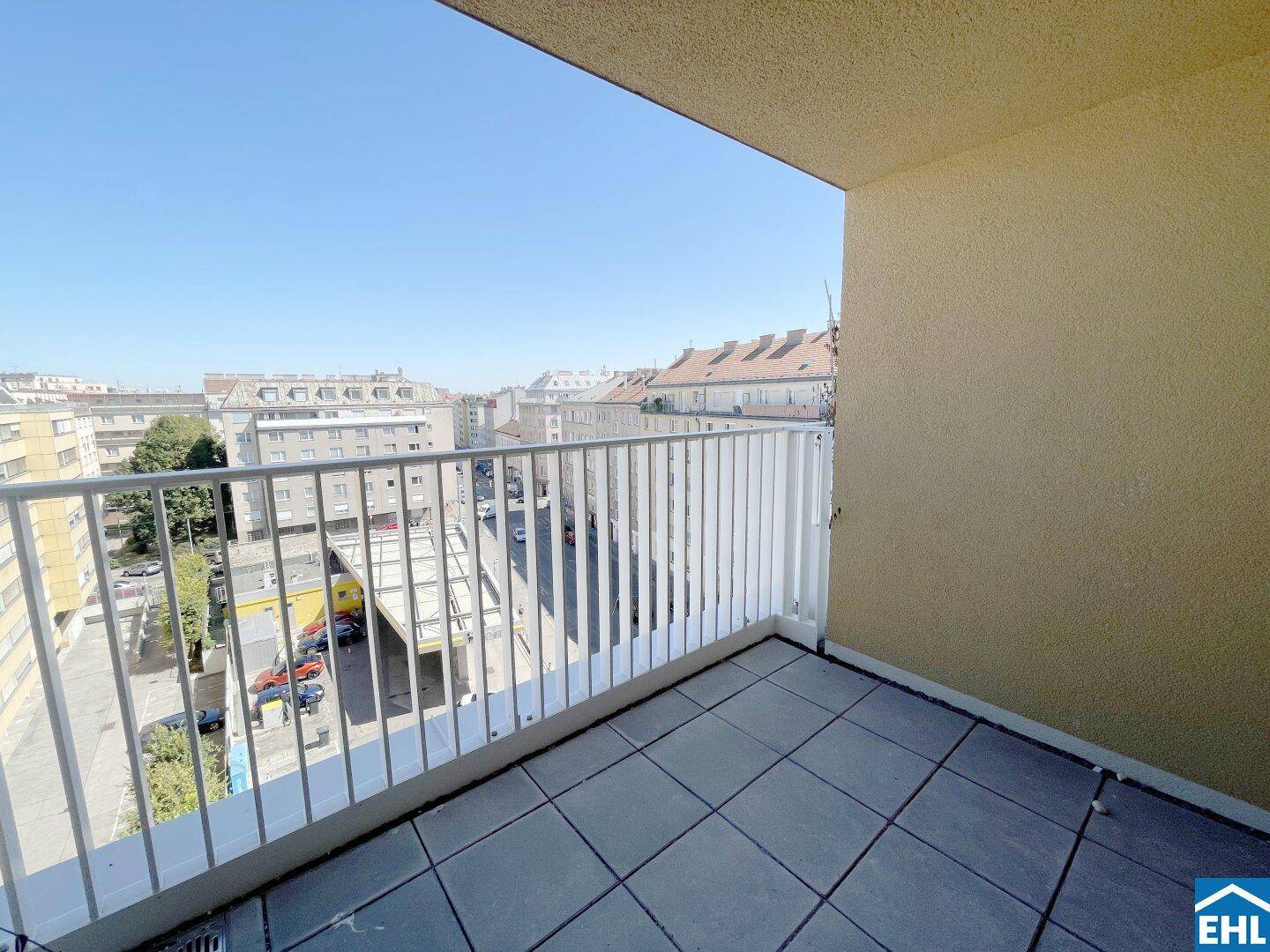 Heller Balkon mit Fliesenboden und weißem Geländer, bietet einen weiten Stadtblick.