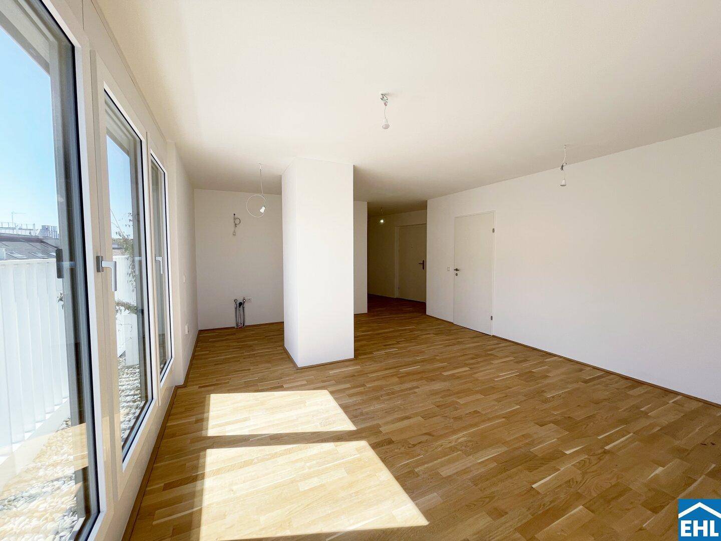 Geräumiges, helles Zimmer mit Holzboden und bodentiefen Fenstern, die einen weiten Blick bieten.