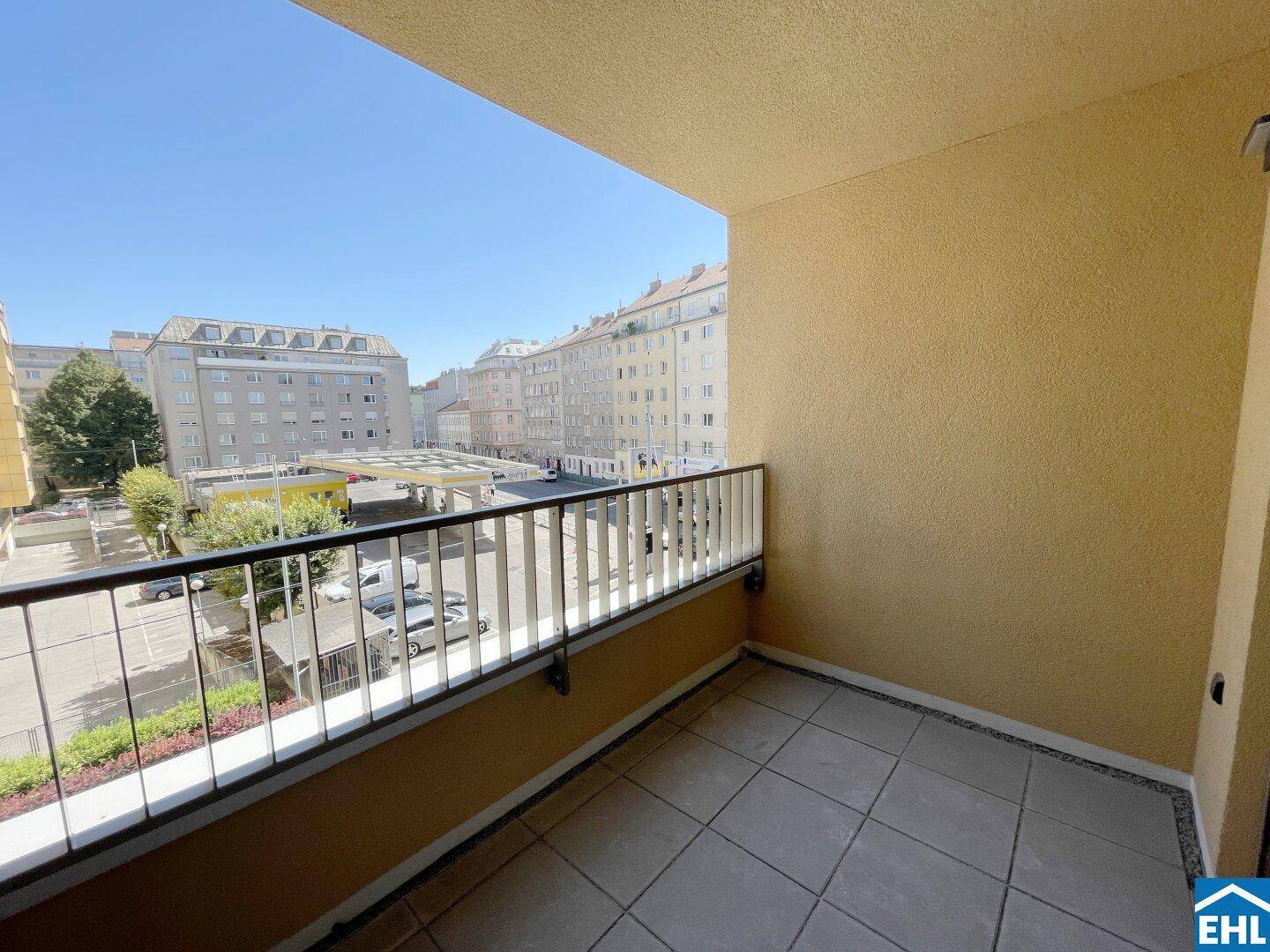 Sonniger Balkon mit Fliesenboden und Blick auf die umliegende Stadtbebauung, ideal zum Entspannen.