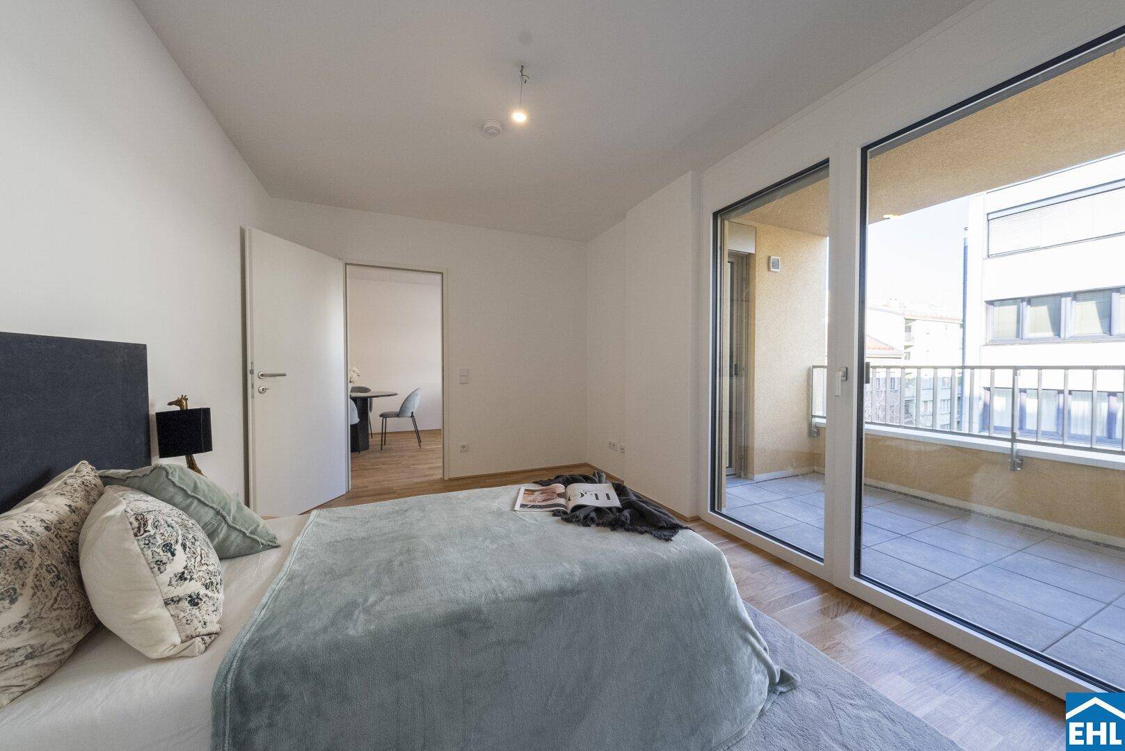 Schlafzimmer mit Parkettboden und großzügigem Zugang zum sonnigen Balkon.
