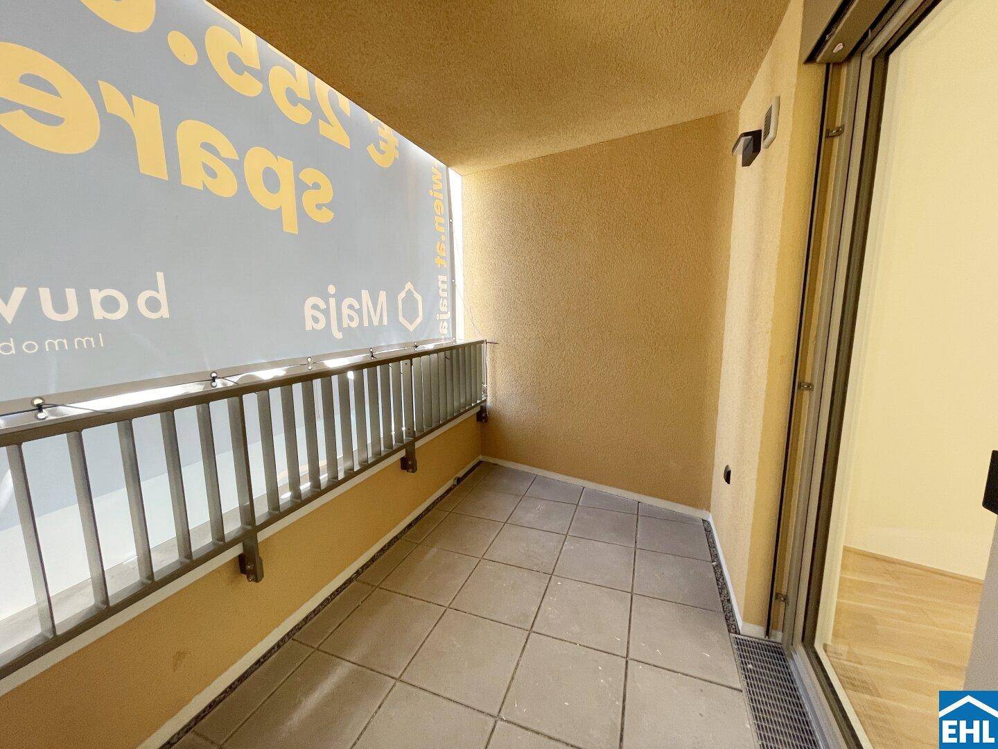 Überdachter Balkon mit Fliesenboden und Metallgeländer, bietet Platz für Entspannung im Freien.
