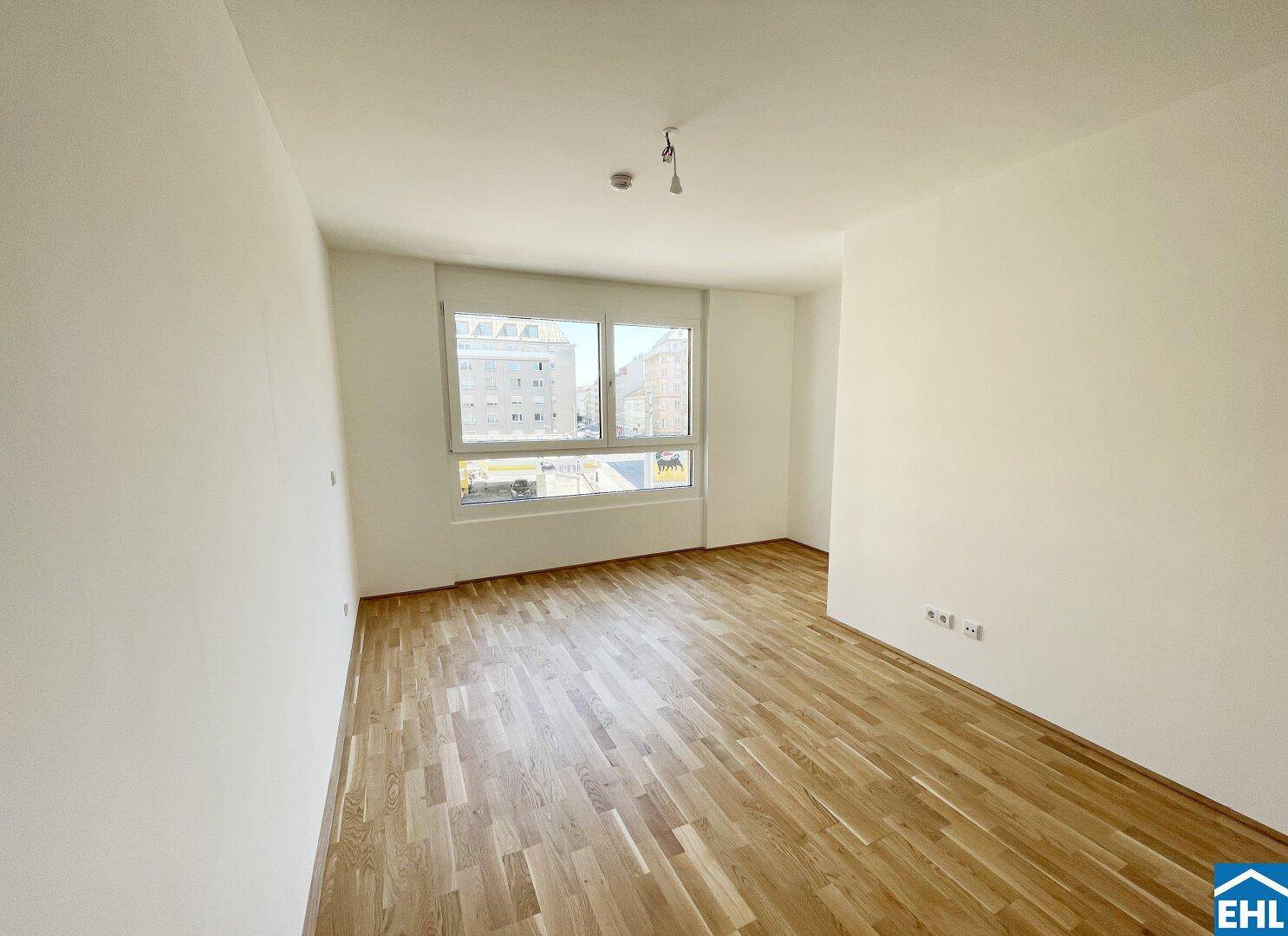 Heller Wohnraum mit Parkettboden und weitem Blick aus dem großen Fenster auf die Stadtumgebung.
