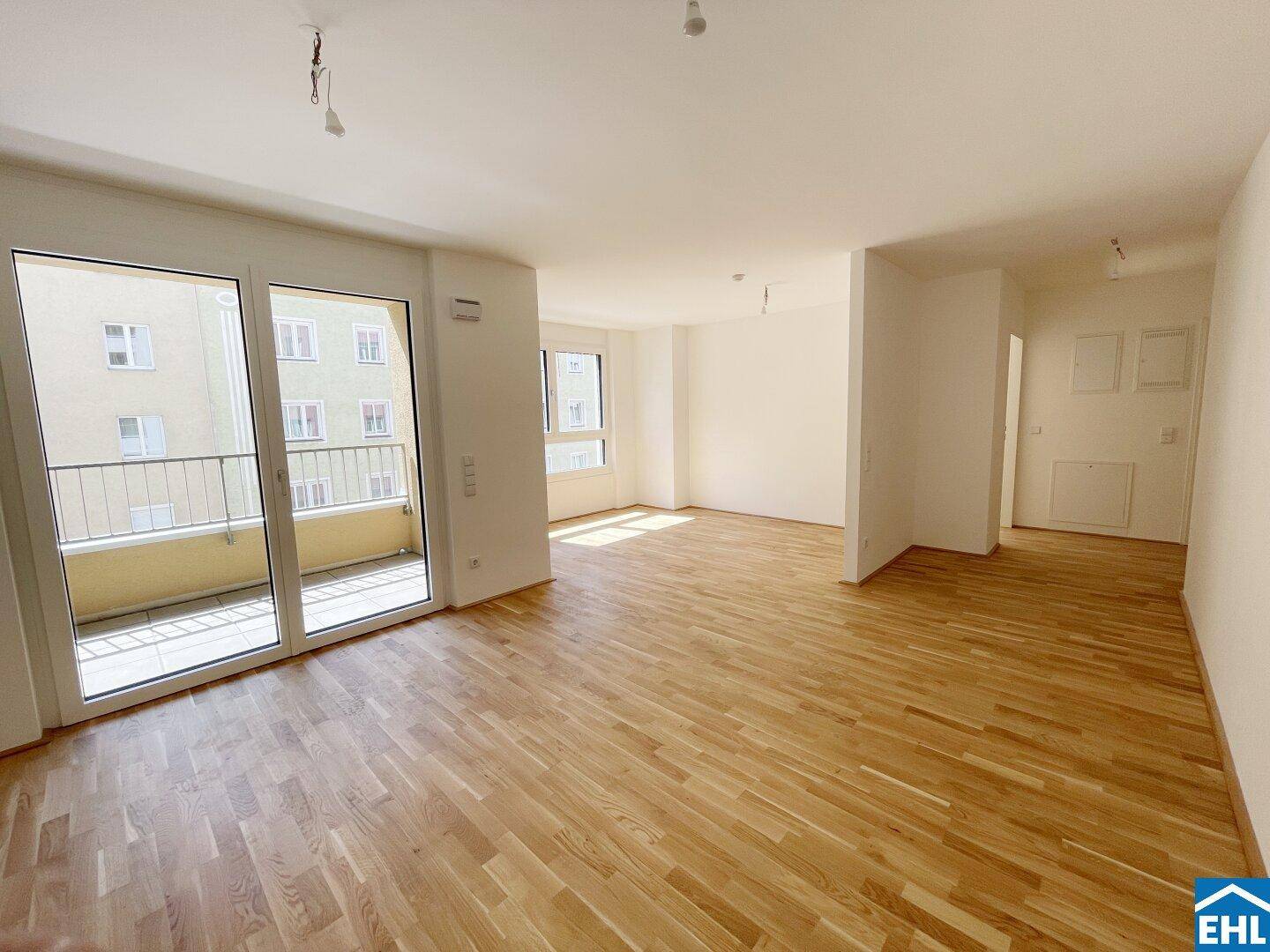 Helles, leeres Wohnzimmer mit Parkettboden und Zugang zu einem Balkon, ideal für offenes Wohnen.