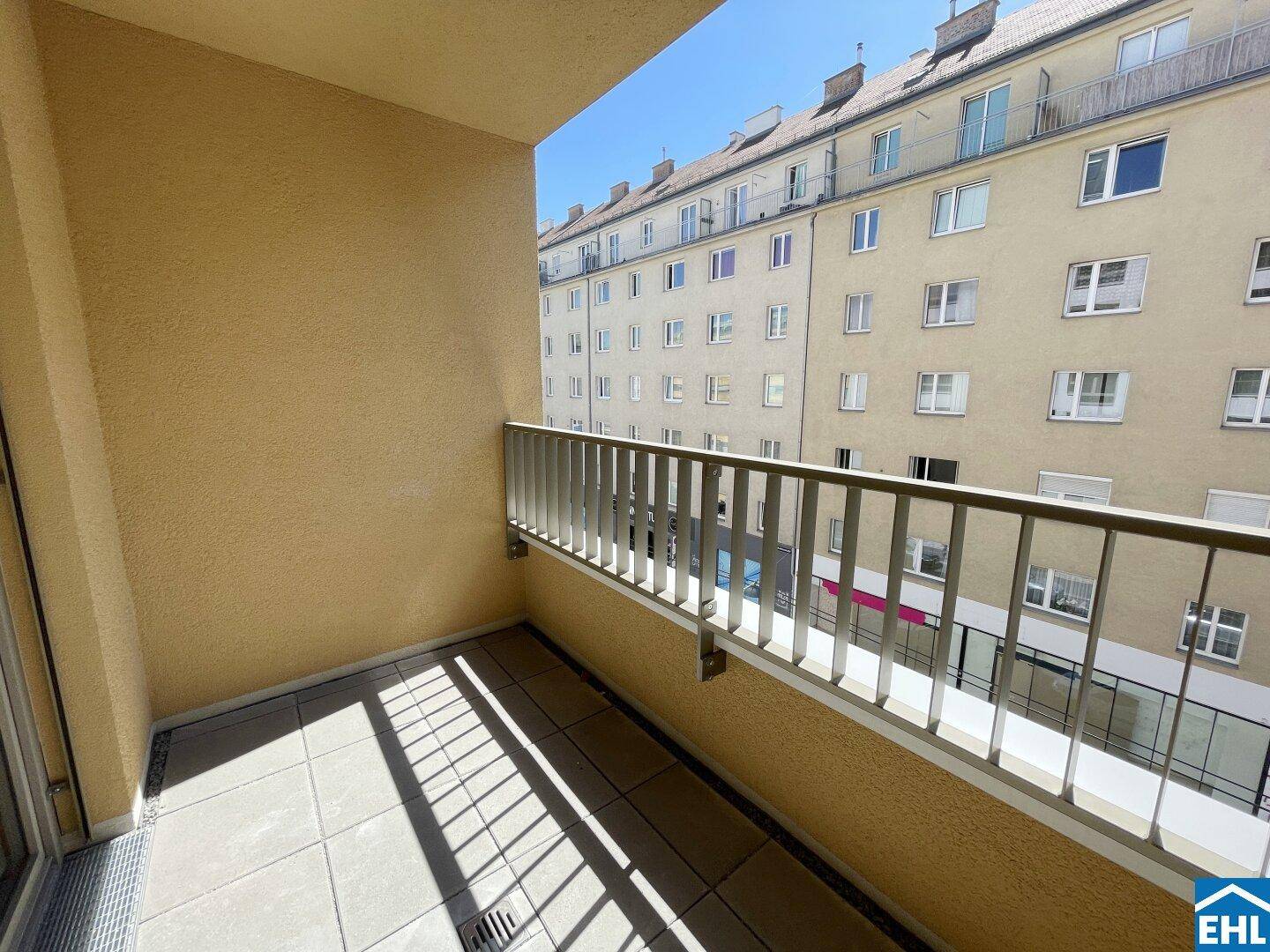 Sonniger Balkon mit Fliesenboden und Blick auf die umliegenden Wohngebäude der Stadt.
