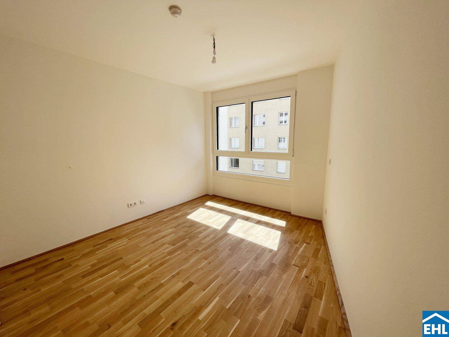 Sonniger Raum mit Parkettboden und großem Fenster, perfekt als Schlafzimmer oder Arbeitszimmer.