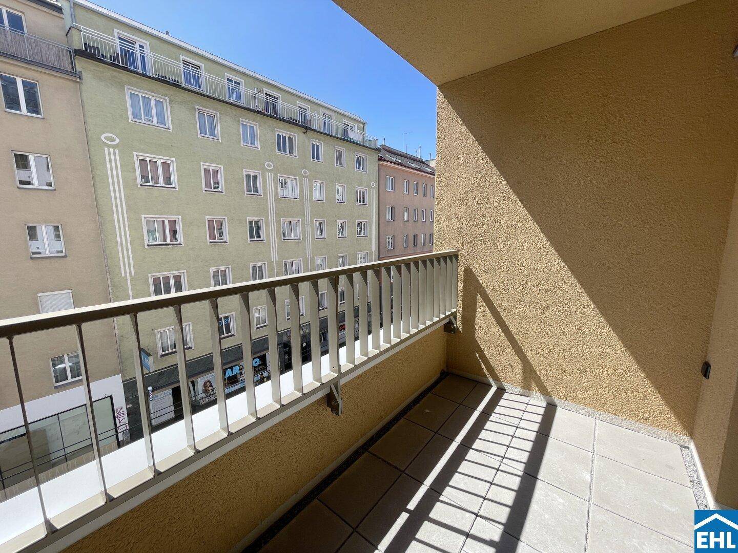 Geräumiger Balkon mit heller Fliesenfläche und freiem Blick auf die städtische Umgebung.