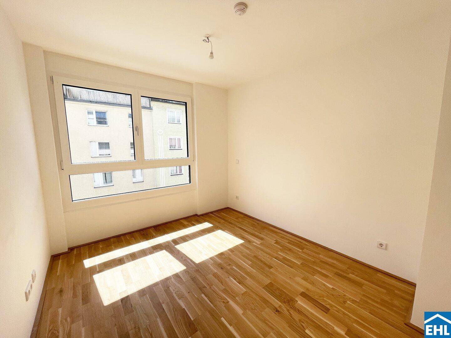 Ruhiges Zimmer mit Parkettboden und großem Fenster, ideal als Schlaf- oder Arbeitszimmer.