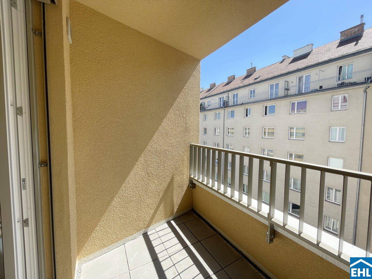 Sonniger Balkon mit Fliesenboden und Blick auf die umliegenden Gebäude.