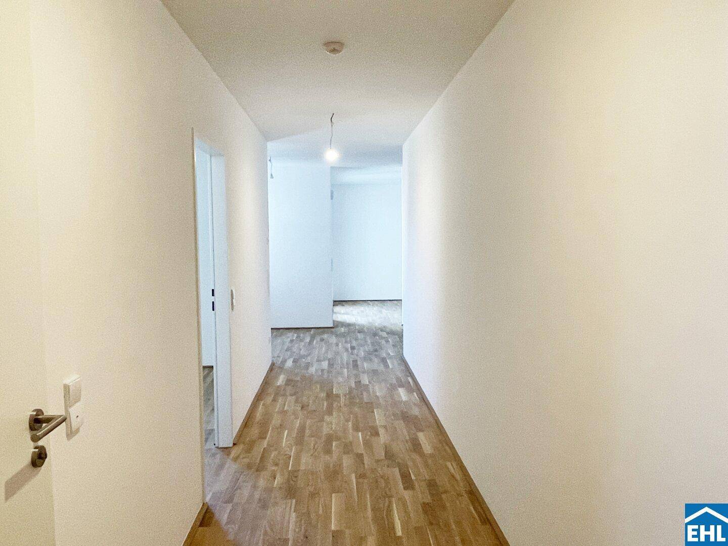 Langer, heller Flur mit Parkettboden, der die verschiedenen Wohnbereiche verbindet.