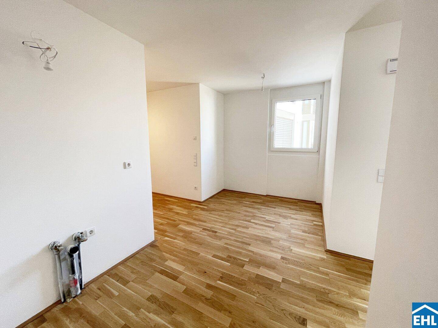 Heller Küchenbereich mit Parkettboden und Anschlüssen für eine zukünftige Einbauküche.