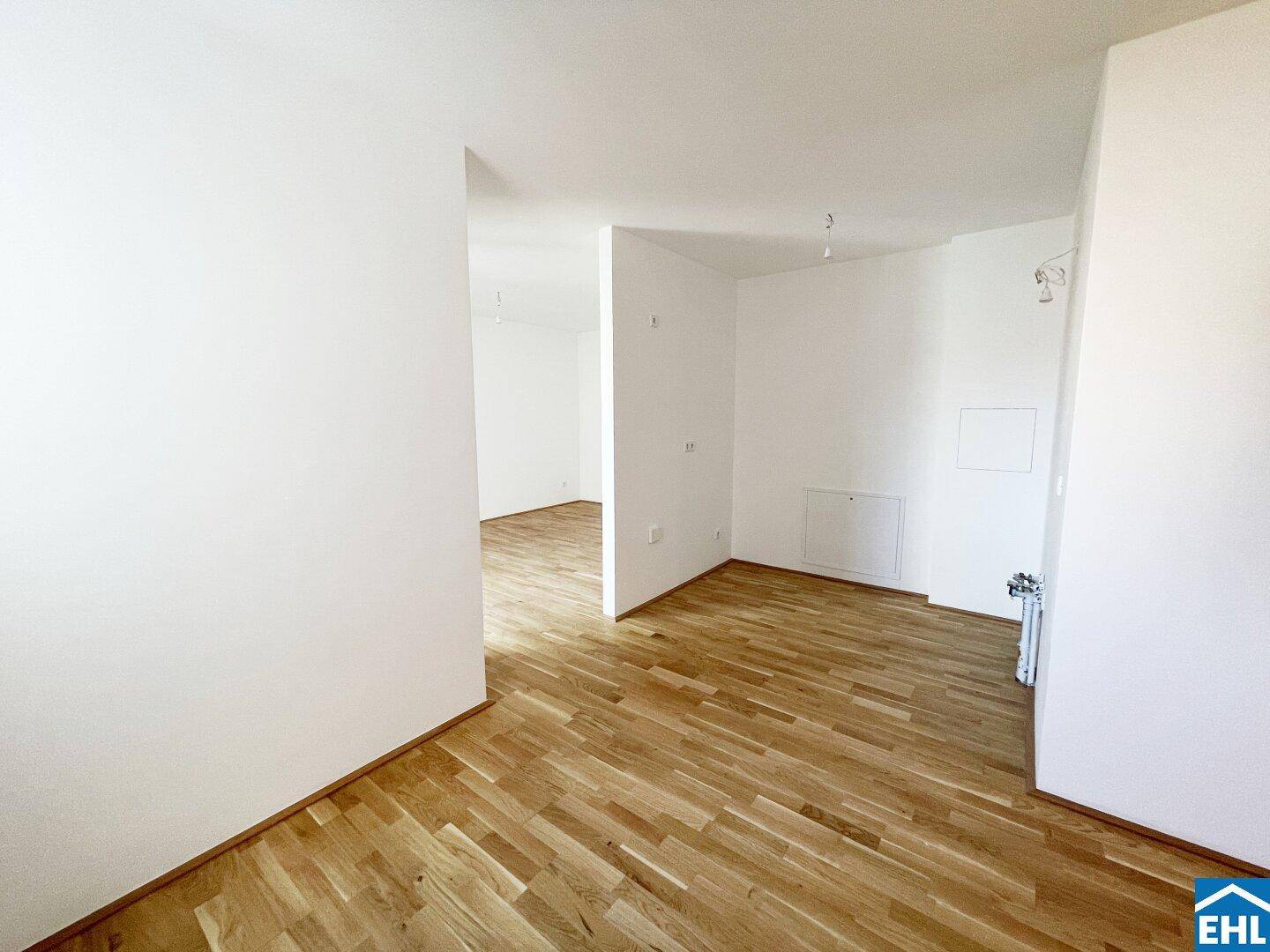 Heller Flurbereich mit Parkettboden, der zu weiteren Zimmern der Wohnung führt.