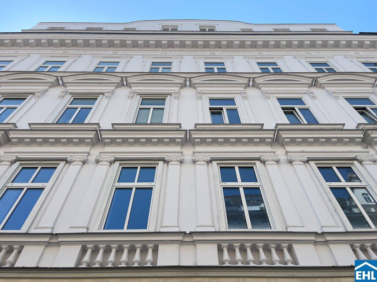 Detailansicht der historischen Fassade mit eleganten Fensterrahmen und Verzierungen, die den gehobenen Stil unterstreichen.