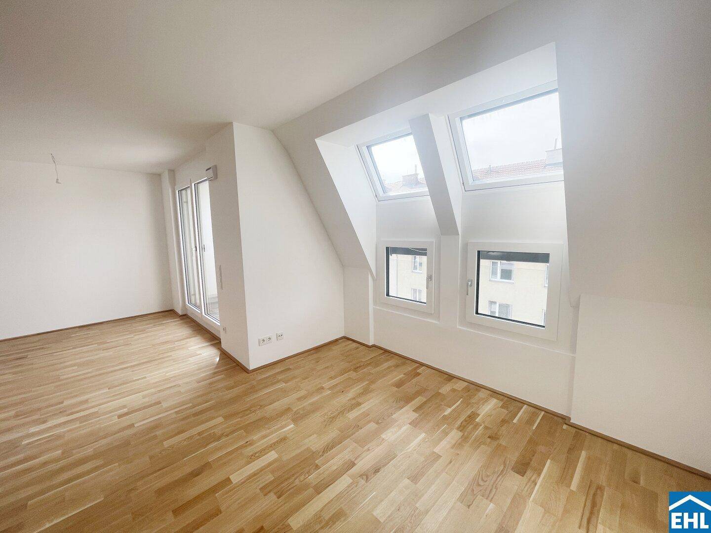 Heller Wohnbereich mit Holzboden und mehreren Dachfenstern, die viel Licht hereinlassen.