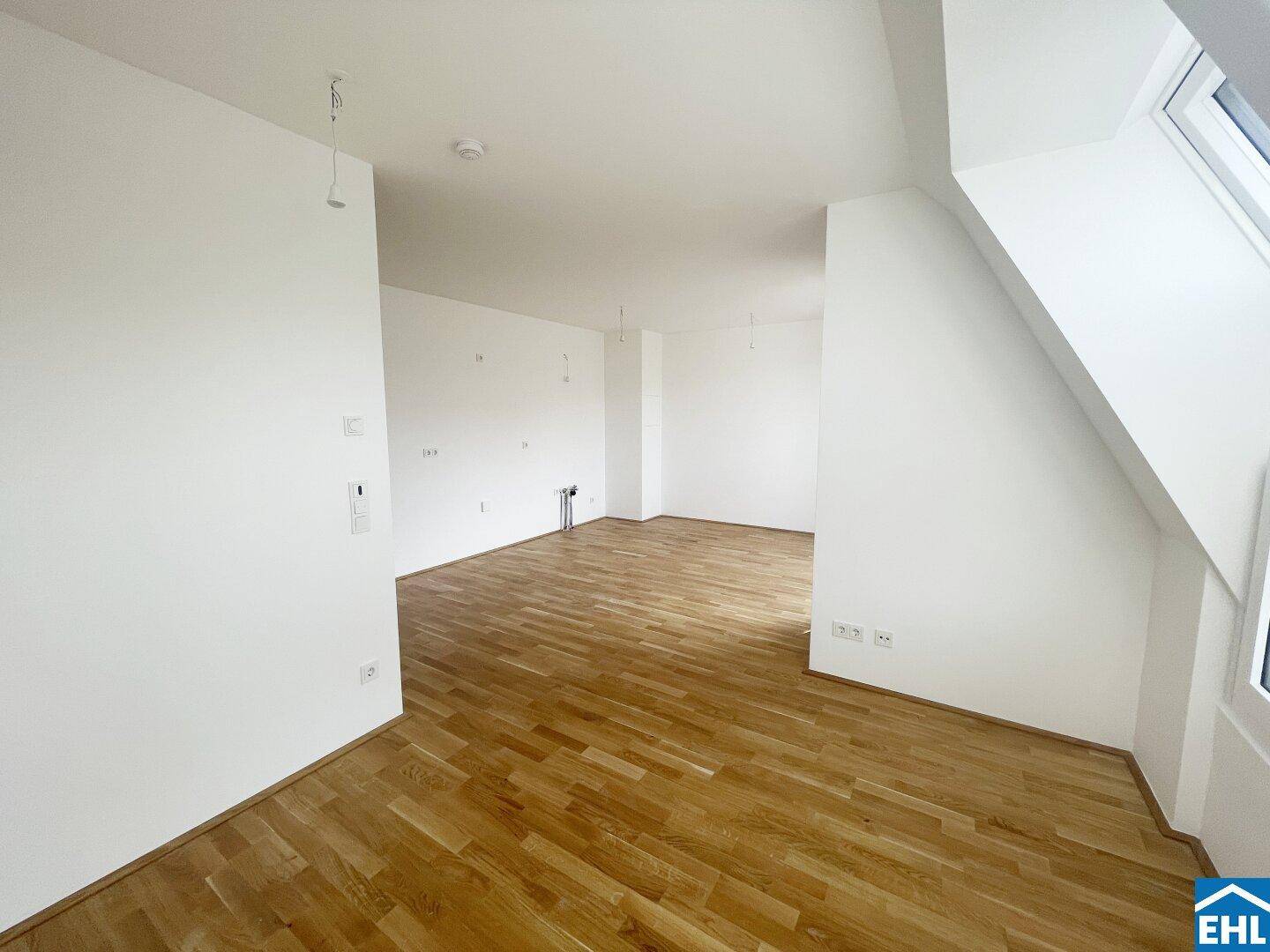 Offener Wohnbereich mit Holzboden und weißen Wänden, bereit für die individuelle Einrichtung.
