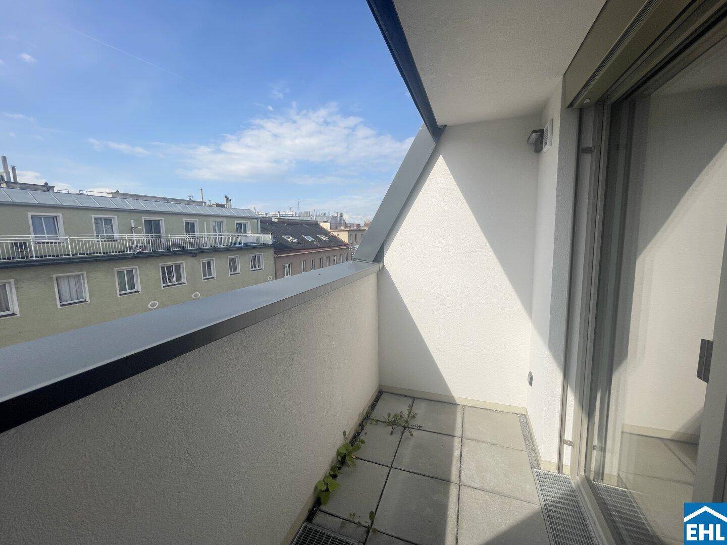 Kleiner Balkon mit Fliesenboden und Blick auf die umliegenden Gebäude.