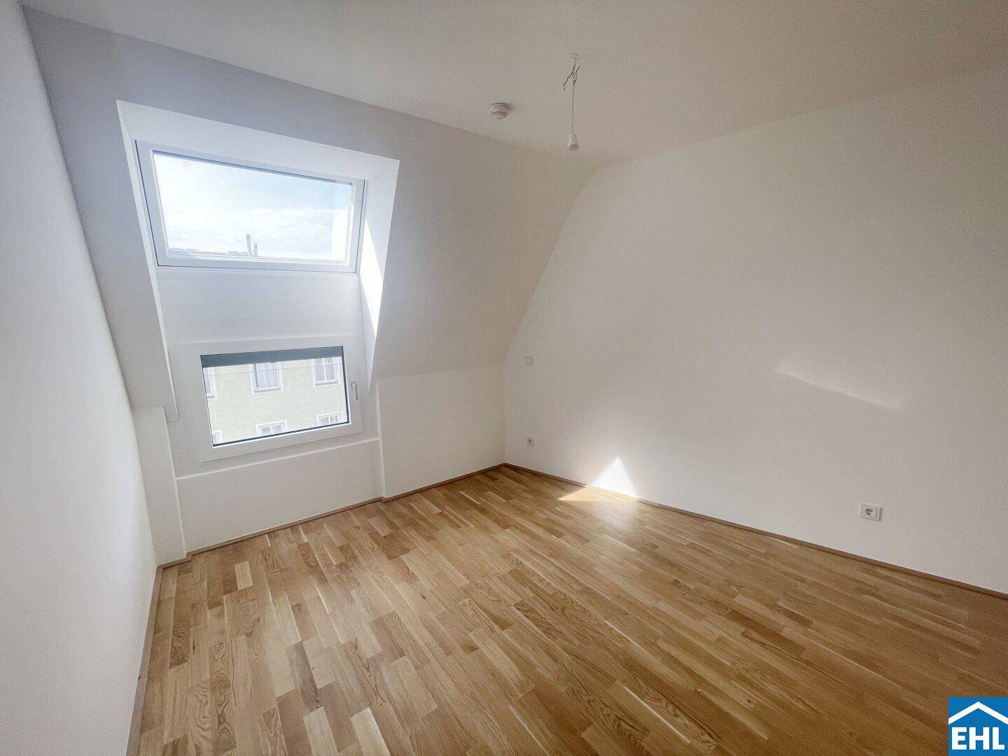 Helles Schlafzimmer mit Holzboden und einem großen Dachfenster für viel Tageslicht.